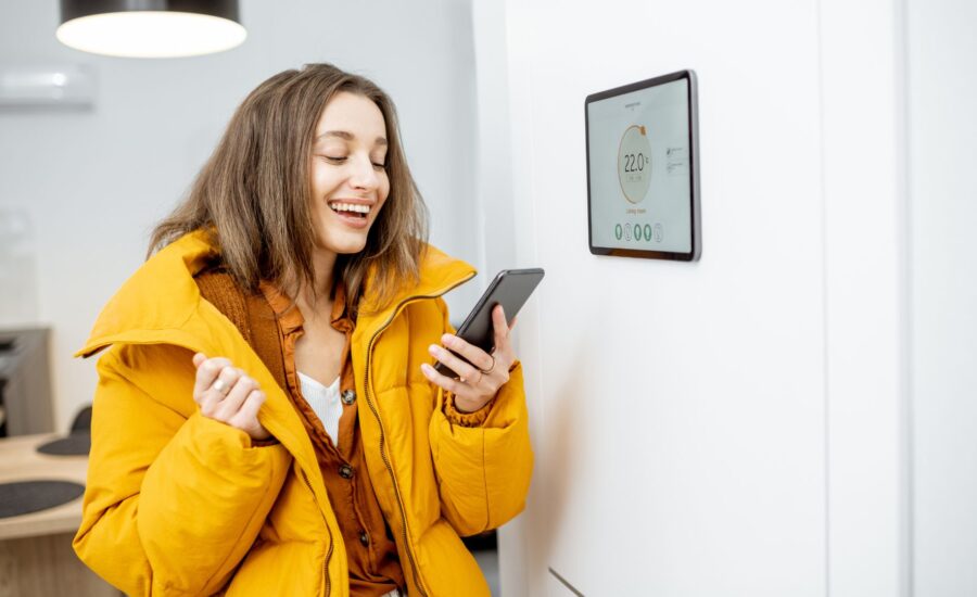 woman in yellow coat with phone inside her home